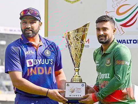 India's captain Rohit Sharma (L) and his counterpart Liton Das (R) hold the tournament trophy during a trophy unveiling program ahead of their first ODI match at the Sher-e-Bangla National Cricket Stadium, in Dhaka on December 3, 2022.