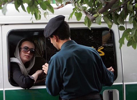 An Iranian policeman speaks with a woman sitting in a police car after she was arrested because of her "inappropriate" clothes during a crackdown to enforce Islamic dress code in the capital Tehran.
