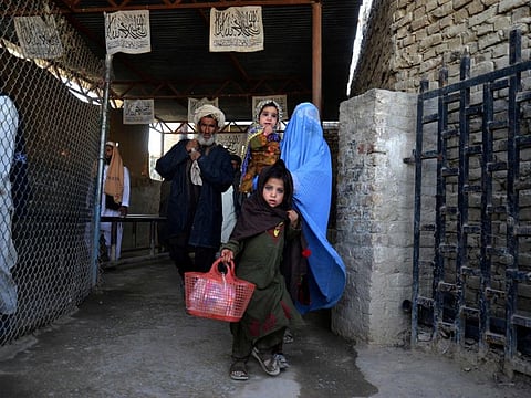 In this picture taken on November 21, 2022, Afghans walk along a fenced corridor as they cross into Pakistan at the border in Spin Boldak. Pakistan is home to more than a million Afghan refugees, and the porous border they share is frequently the scene of clashes.