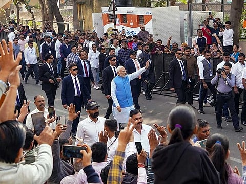 Prime Minister Narendra Modi waves to supporters on his way to the polling booth to cast his vote for the second phase of Gujarat Assembly elections, in Ahmedabad on Monday, December 5, 2022.