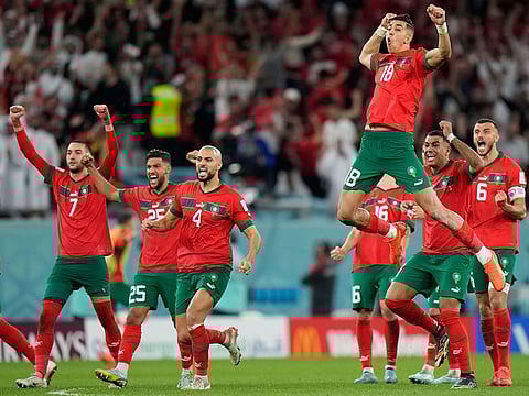 Morocco's Jawad El Yamiq, top, celebrates with team mates after the penalty shootout at the World Cup round of 16 soccer match between Morocco and Spain.