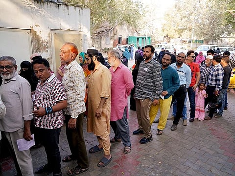 Voters wait in queues to cast their vote for the second phase of the Gujarat Assembly Elections, in Ahmedabad on Monday