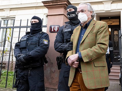 Masked police officers lead Heinrich XIII Prince Reuss, right, to a police vehicle during a raid against so-called 'Reich citizens' in Frankfurt, Germany, Wednesday, Dec. 7, 2022.