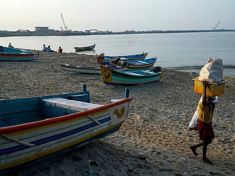 A port being constructed by the Adani group is seen behind as a fisherman leaves the shore at Vizhinjam on the Arabian Sea coast in Kerala, India, Tuesday, Dec.6, 2022.