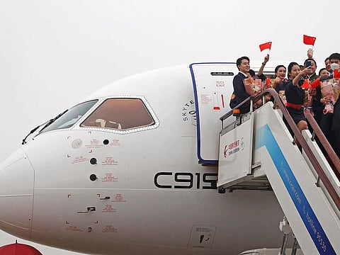 Crew members wave Chinese national flags out of the C919 aircraft, China's first domestically produced large passenger jet.