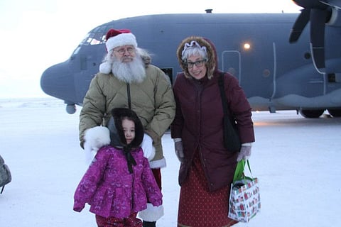 Santa and Mrs. Claus pose with a child who braved winds chills of about minus 25 degrees to greet them when they landed on Nov. 29, 2022, in Nuiqust, Alaska.