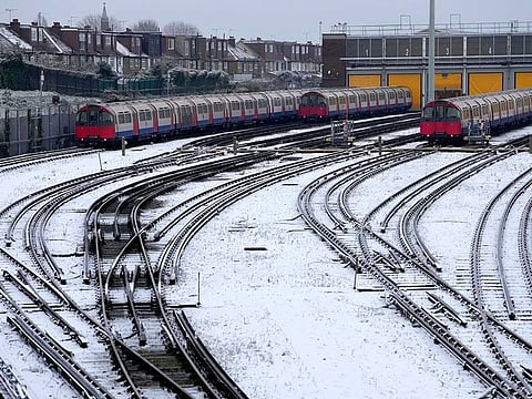 Snow covers the tracks as tube trains are parked in London, Monday, Dec. 12, 2022. Snow and ice have swept across parts of the UK, with cold wintry conditions set to continue for days.