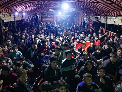 Displaced Syrian men and boys watch the football match between Morocco and Portugal, during the Qatar 2022 World Cup tournament, inside a large tent set up by volunteers of a humanitarian organisation for fans in the camp of Barisha in the northern part of the rebel-held Idlib province, on December 10, 2022.