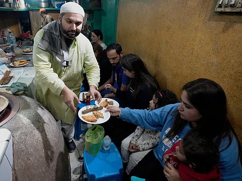 Bilal Sufi, left, owner of Baking Virsa eatery, serves traditional kebabs and naan bread in Lahore.