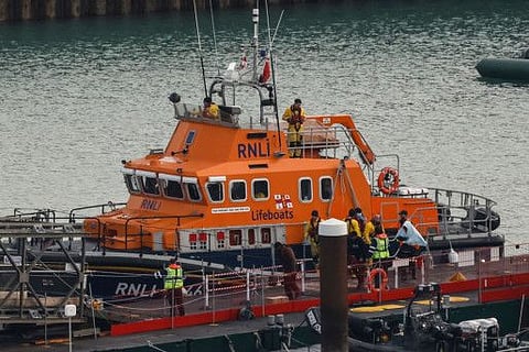 Migrants picked up at sea while attempting to cross the English Channel, are escorted off from the UK Royal National Lifeboat Institution (RNLI) lifeboat at the Marina in Dover, southeast England, on December 14, 2022.