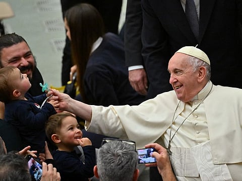 Pope Francis holds a toddler's dummy as he meets with attendees during the weekly general audience on December 14, 2022 at Paul-VI hall in The Vatican.
