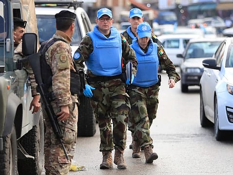 Irish UN peacekeepers pass a Lebanese soldier, left, as they arrive to investigate the scene where unidentified open gunfire came on a UN peacekeeper convoy in the Al Aqbiya village, south Lebanon, Thursday, Dec. 15, 2022.