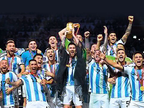 Argentina's captain and forward #10 Lionel Messi (C) lifts the FIFA World Cup Trophy as he celebrate with teammates winning the Qatar 2022 World Cup final football match between Argentina and France at Lusail Stadium.