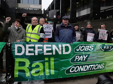 Mick Lynch, general secretary of the Rail, Maritime and Transport union (RMT), centre, joins members of rail workers during a strike outside Euston station in London, on Dec. 13, 2022. The British government said Sunday Dec. 18, 2022 it will dispatch 1,200 troops to fill in for striking ambulance drivers and border staff as multiple public sector unions walk off the job in the week before Christmas.