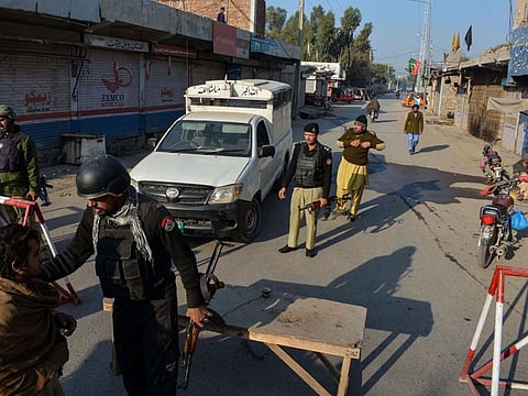 Police stand guard along a road they blocked after Taliban militants seized a police station in Bannu on December 19, 2022.
