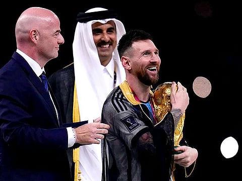 Argentina's Lionel Messi holds up the trophy flanked by FIFA President Gianni Infantino and the Emir of Qatar Sheikh Tamim bin Hamad Al Thani after winning the World Cup final soccer match between Argentina and France at the Lusail Stadium in Lusail, Qatar, Sunday, Dec.18, 2022.