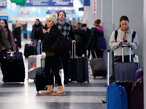 A traveler, right, checks on her cellphone as other travelers walk through Terminal 3 at O'Hare International Airport in Chicago, Thursday, Dec. 22, 2022. (AP Photo/Nam Y. Huh)