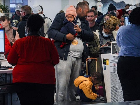 Southwest Airlines ticket holders Cameron Bradley, center, and his wife Kamilah Bradley, second from right, with their children Malaki, 3, and Kehlani, 8 months, try to rebook a flight to Atlanta after a cancellation at Laguardia Airport, Friday Dec. 23, 2022, in New York. "Literally we were in line trying to check our bags and the flight got cancelled," said Cameron, hoping to reach Atlanta for Kehlani's first meeting with her grandmother. "We can't fly anywhere- the nearest time would be after Christmas." (AP Photo/Bebeto Matthews)