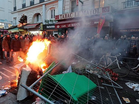 Members of Kurdish community stand next to a barricade on fire as they clash with police officers at the crime scene where a shooting took place in Paris, Friday, Dec. 23, 2022. Skirmishes erupted in the neighbourhood a few hours after the shooting, as members of the Kurdish community shouted slogans against the Turkish government, and police fired tear gas to disperse an increasingly agitated crowd. A shooting targeting a Kurdish cultural center in Paris Friday left three people dead and three others wounded.