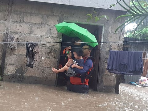 Rescuers evacuating a child from a flooded area in Ozamiz City, Misamis Occidental.