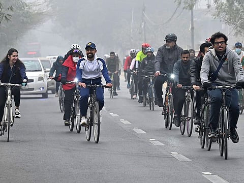 Cyclists take part in a pollution and smog awareness campaign as they ride along a street towards the Wagah border, in Lahore on December 25, 2022.