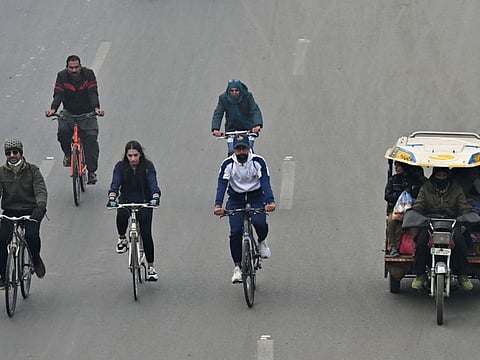 Cyclists take part in a pollution and smog awareness campaign as they ride along a street towards the Wagah border, in Lahore on December 25, 2022.