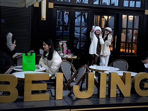 Residents pose for selfies outside a popular bakery in Beijing, Wednesday, Dec. 28, 2022. China says it will resume issuing passports for tourism in another big step away from anti-virus controls that isolated the country for almost three years, setting up a potential flood of Chinese going abroad for next month's Lunar New Year holiday. (AP Photo/Ng Han Guan)
