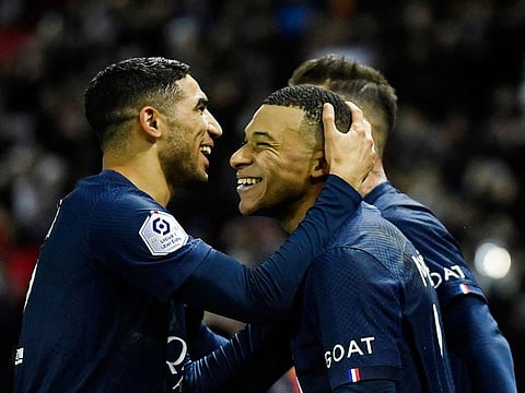 Paris Saint-Germain's French forward Kylian Mbappe (C) celebrates after scoring a penalty with PSG's Moroccan defender Achraf Hakimi (L) during the French L1 football match between PSG FC and RC Strasbourg Alsace at The Parc des Princes stadium in Paris on December 28, 2022.
