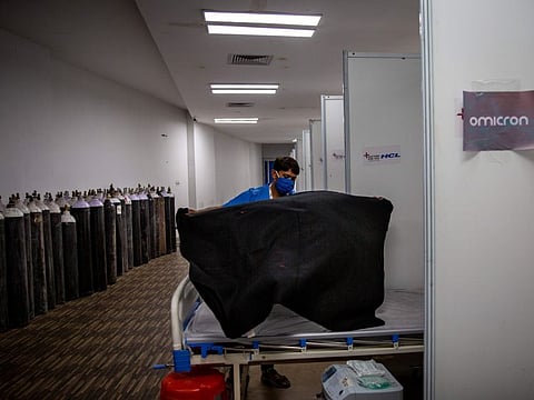 A paramedic make beds at a makeshift COVID-19 care centre at an indoor sports stadium in New Delhi.