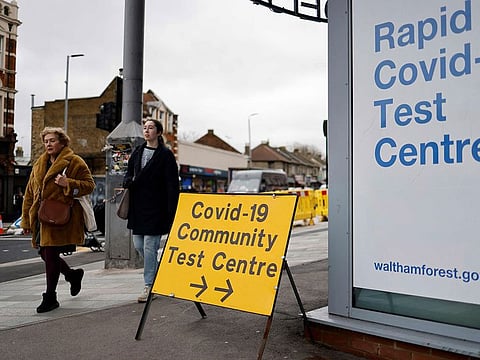 Pedestrians walk past a directional sign for a Covid-19 test centre on Hoe Street in Walthamstow, north London.