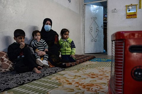 Alia Abdel-Razak, a woman deprived of crucial civil status documents, is pictured with 3 of her children in her home in Iraq's northern city of Mosul on December 11, 2022. Many in Mosul struggle with endless red tape, but also the fallout from the gruelling battle to defeat the Islamic State group, to obtain documents like marriage and birth certificates.