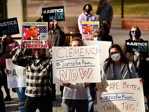 People hold signs in support of truck driver Rogel Aguilera-Mederos during a rally on the west steps of the state capitol Wednesday, Dec. 22, 2021 in Denver