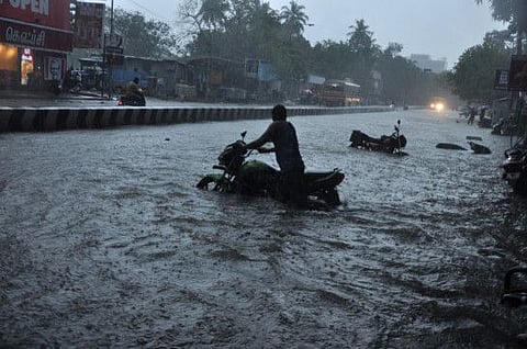 A commuter wades through a waterlogged street in Chennai on Thursday.