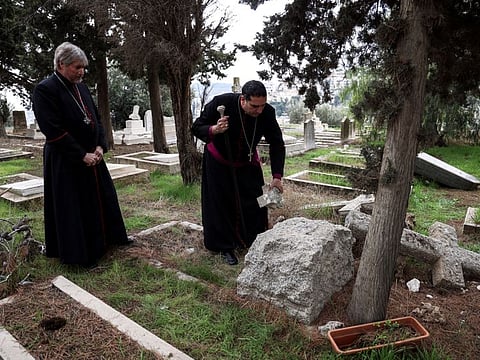 Archbishop Hosam Naoum inspects a vandalised tombstone at the Protestant Mount Zion Cemetery in Jerusalem January 4, 2023.