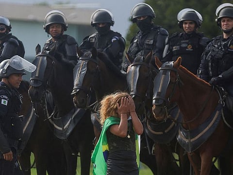 A demonstrator reacts next to security forces as supporters of Brazil's former President Jair Bolsonaro leave a camp in front of the the Army Headquarters in Brasilia, Brazil, January 9, 2023.