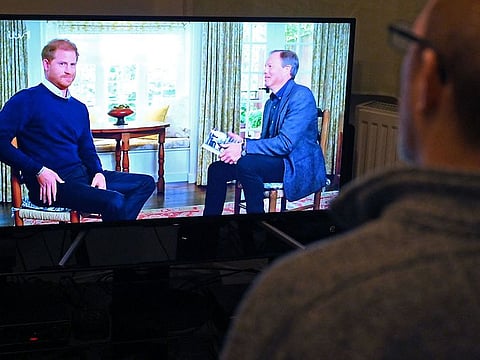 A member of the public poses in his front room in Manchester, north-west England, watching a television interview broadcast on ITV, being given by Britain's Prince Harry, Duke of Sussex on January 8, 2023, ahead of the publication of his book, 'Spare'.