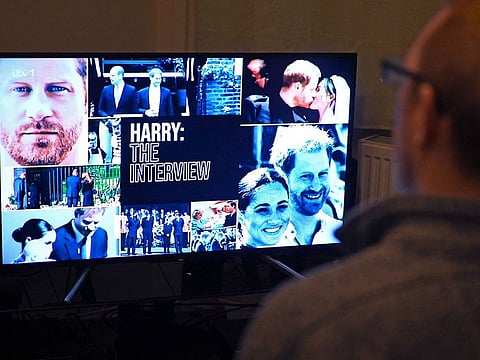 A member of the public poses in his front room in Manchester, north-west England, watching a television interview broadcast on ITV, being given by Britain's Prince Harry, Duke of Sussex on January 8, 2023, ahead of the publication of his book, 'Spare'.