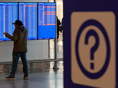 A person talks on a mobile phone by a video board showing flight delays and cancellations at Ronald Reagan Washington National Airport in Arlington, Virginia, on January 11, 2023.