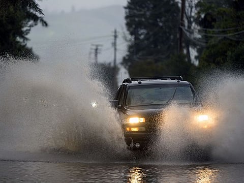 Cars drive through a flooded street in Watsonville, California.