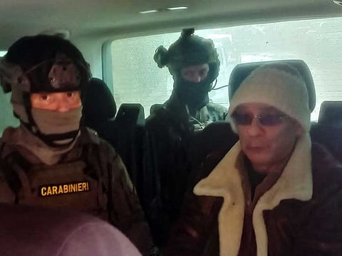 This handout picture released on January 16, 2023 by the Ufficio Stampa Comando Generale Carabinieri shows Italy's top wanted mafia boss, Matteo Messina Denaro (R), being escorted in a vehicle by carabinieri after he was arrested in his native Sicily after 30 years on the run.