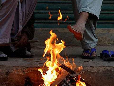 Labourers keep themselves warm near a fire during a cold morning, as they wait for work at the market in Karachi, Pakistan January 13, 2023. Reuters