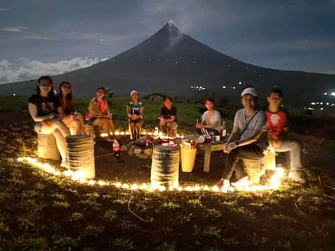 People gather around a bonfire at the foot of Mount Mayon (height: 2,463 m), at "Hobbit Hill" in Albay province, about 10 hours by car from the capital Manila.