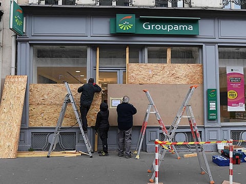 Workers board up the windows of an insurance group branch located on the route of a demonstration.