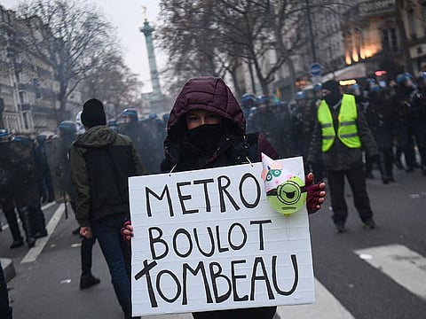 A demonstrator holds a sign reading 'Metro, job, tomb' during a rally called by French trade unions in Paris on January 19, 2023.