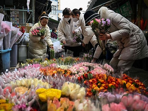 People buy flowers in a market in Wuhan, in China's central Hubei province on January 21, 2023, ahead of the start of the Lunar New Year, which ushers in the Year of the Rabbit on January 22.