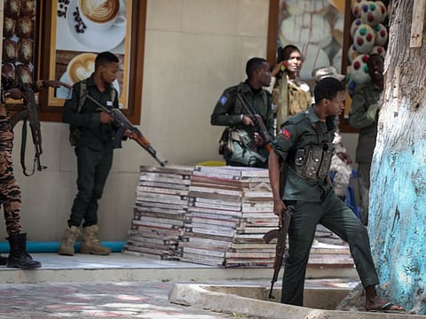 Police officers take up positions outside of the Mayor's office where an ongoing gun battle erupted following a reported explosion, in Mogadishu, on January 22, 2023.