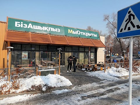 A view shows a fast food restaurant, which used to operate under the McDonald's brand and reopened with no branding weeks. A sign reads: 'We are open'.
