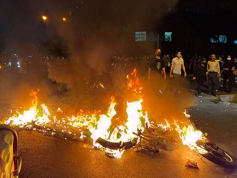 Demonstrators gather near a motorbike on fire during a protest for Mahsa Amini, a woman who reportedly died after being arrested by the Islamic republic's "morality police", in Tehran on September 19, 2022.