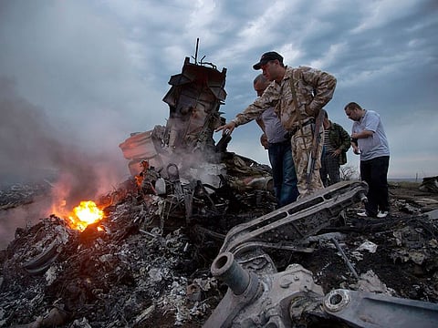 FILE - People inspect the crash site of a passenger plane near the village of Hrabove, Russian-controlled Donetsk region of Ukraine.
