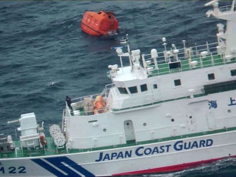 A coast guard vessel next to a lifeboat (top) from the Jin Tian cargo ship.